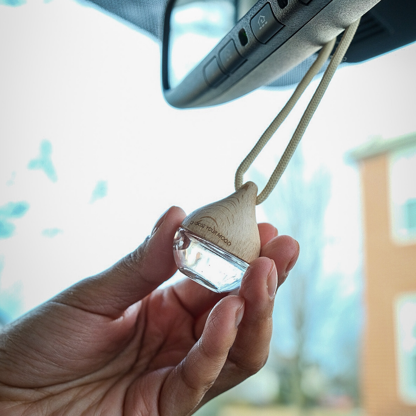 Hand holding a wooden car air freshener 