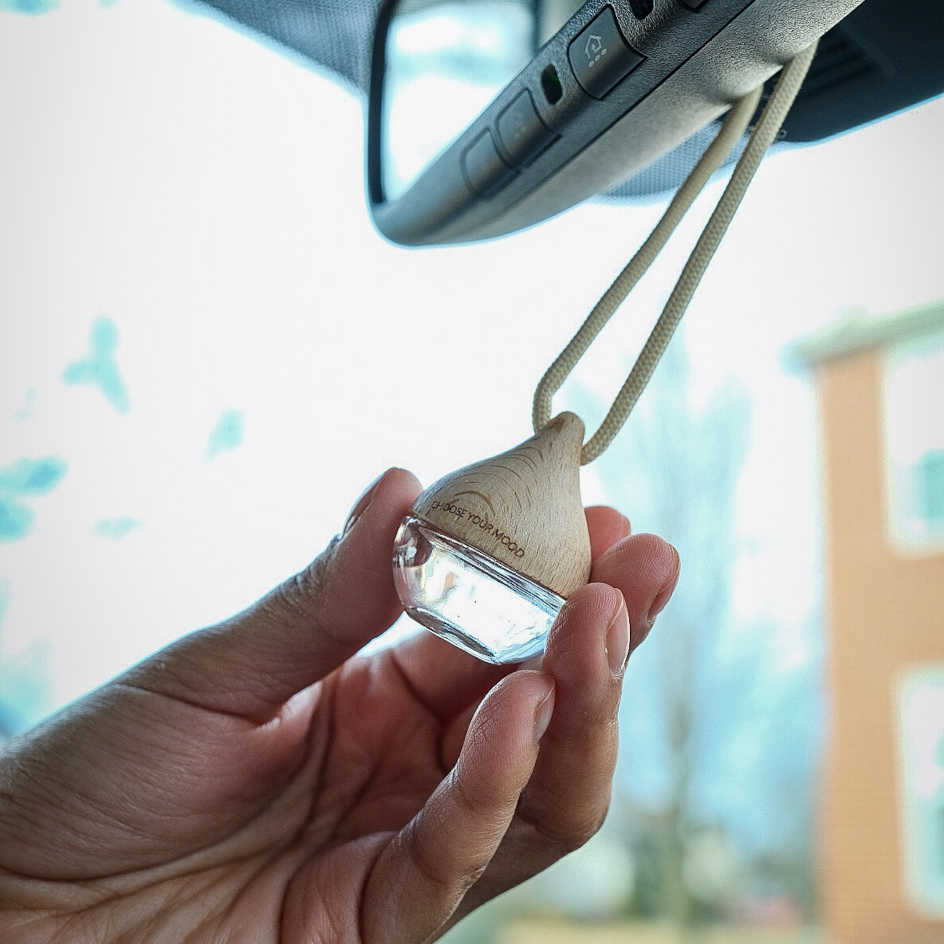 Hand holding a wooden car air freshener 